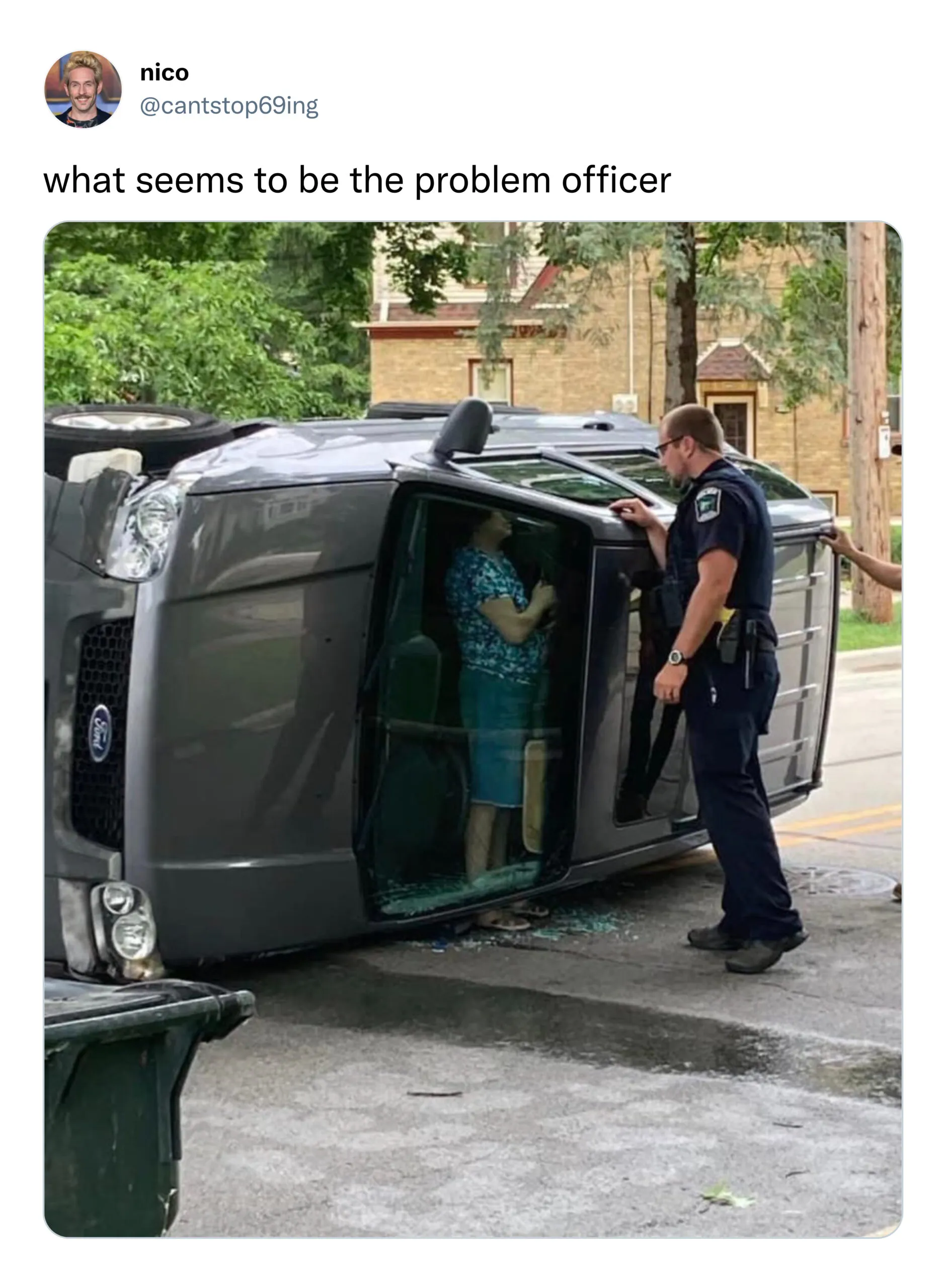 A woman standing up in her car after an accident while talking to police